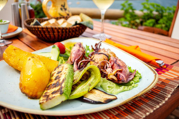 Grilled squid stuffed with vegetables and lemon on the table in seafront.