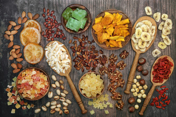 Dried fruit and nut collection on rustic wood background. Health food high in antioxidants, protein, omega 3. minerals, vitamins and anthocyanins. Flat lay.