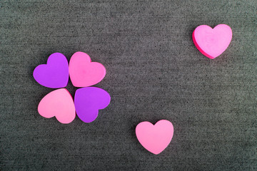 Six pink and mauve hearts on dark grey textile background, top view with space for text above, selective focus