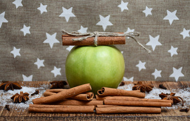 An apple, cinnamon sticks, star-anise, cloves and snow
