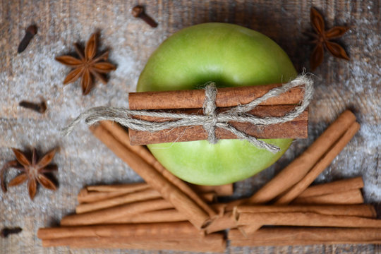 Top view: an apple, cinnamon sticks, star-anise, cloves and snow