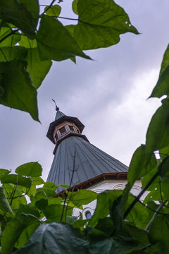 Anchient tower top among green leaves on a cloudy day. Novospassky monastery in Moscow.  Russia..