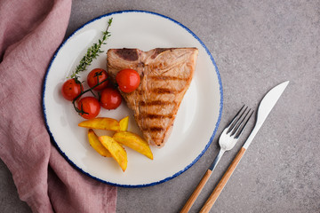 Veal tbone steak with potato wedges and tomatoes