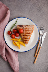 Veal tbone steak with potato wedges and tomatoes