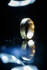 Gold wedding ring on black glass