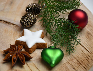 A fir tree branch, a star-shaped cookie, a star-anise, cones & Christmas-tree decorations (ball & a heart)