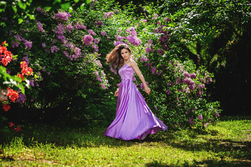 Obraz na płótnie Canvas girl with in a long dress spinning in a blooming orchard, young woman smiling