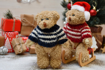 A Teddy Bear takes another one for a sledge drive on a background of a Christmas tree & boxes with Christmas presents