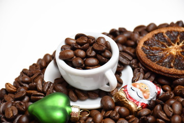A small cup, coffee beans, a green heart, Santa Claus and a dried orange slice