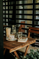 cup of coffee, a book, and a glass on the table and chair