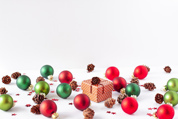 Decorative snow and christmas balls of red and green colors, pine cone, small red stars around and brown present box. Xmas concept with copy space