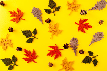Fototapeta na wymiar View of autumn leaves and pine cones on yellow background. Halloween concept, flat lay