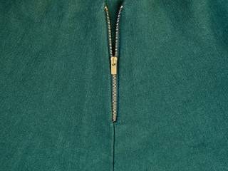 Golden zipper on green clothes. Close-up