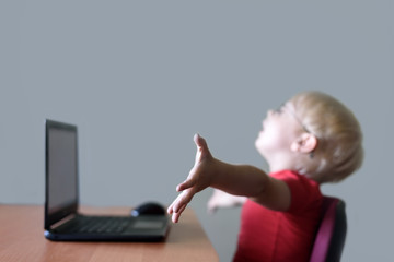 Blurred portrait of a blond boy at a laptop. Joy, end of work