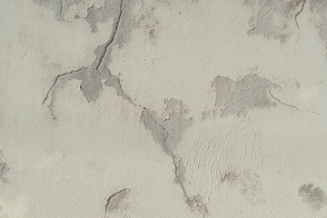 Old plastered beige wall with cracks and peeling. The concept of strength and time