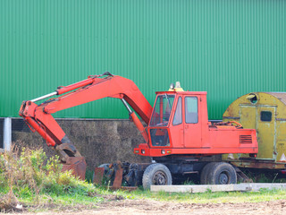 Excavator in the parking lot opposite the hangar