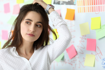 Portrait of pretty businesswoman standing near white board with empty colorful sticker and touching...