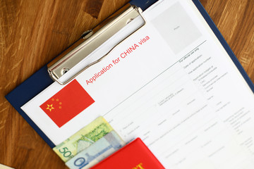 Red passport lie against china application form backgroung cloceup.