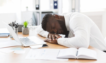 Exhausted african worker sleeping on his workplace