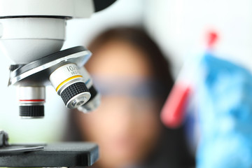 Fototapeta na wymiar Scientific microscope lens with female analyst in background close-up