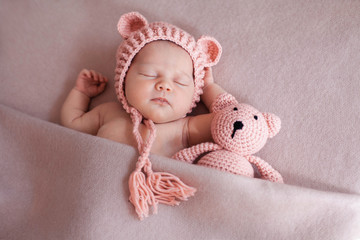 Cute newborn baby girl sleeping with teddy bear.