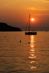 sunset on the sea with sailboats and island silhouette
