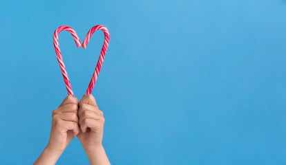 Candy in shape of heart in woman hands on blue background
