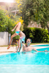 Happy family having fun together in outdoors swimming pool