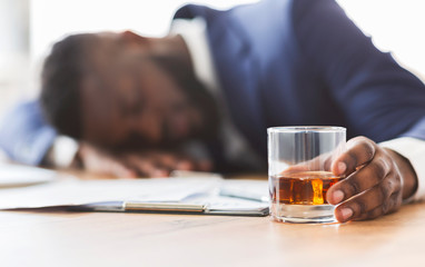 Drunk employee with glass of whiskey sleeping at working place