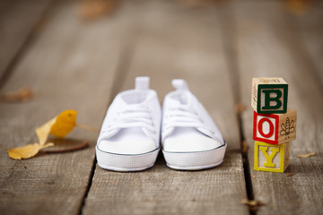 Waiting for baby-boy. Little white baby's bootees on wooden floor. Autumn scene. Pregnancy,...