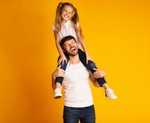 Father Giving Daughter Piggyback Ride Smiling At Camera, Studio Shot