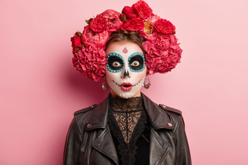 Shocked terrified young woman has scary ghost face, wears artistic makeup for Day of Dead holiday,...