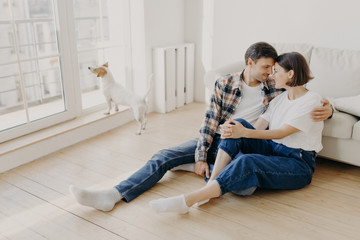 Happy newlywed couple move in new apartment, rejoice having spare time together, embrace and touch...