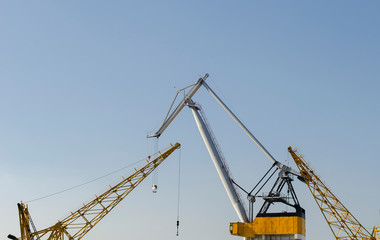 Yellow construction cranes close-up. Blue sky and white clouds. Place for text. Selective focus image. Copy space.