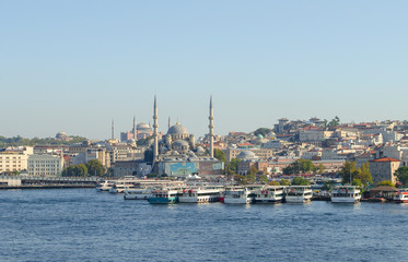Fototapeta na wymiar Touristic boats in Golden Horn bay of Istanbul and view on Suleymaniye mosque. View of old city, mosque, red tile roofs and green trees. Clear blue sky. Turkey, Istanbul