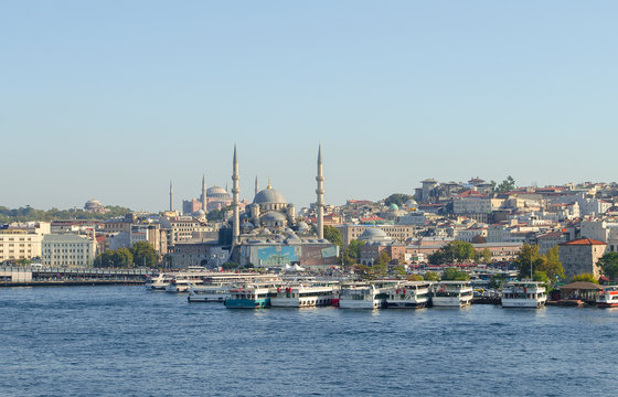 Touristic boats in Golden Horn bay of Istanbul and view on Suleymaniye mosque. View of old city, mosque, red tile roofs and green trees. Clear blue sky. Turkey, Istanbul
