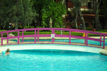 Swimming pool with stair and wooden deck at hotel.