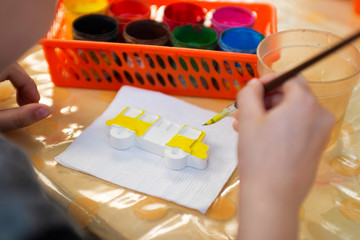 Child is painting figures with watercolor paints. Manual work. Hand maid. Children's holiday. Kids hobby and creativity