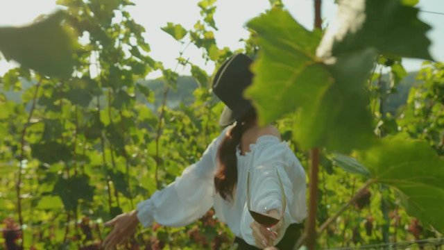 Happy young woman enjoying freedom and nature running through gorgeus grape vineyard on summer holiday tour.