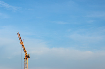 Yellow crane on blue cloudy sky. Crane at left corner of photo with copy space.