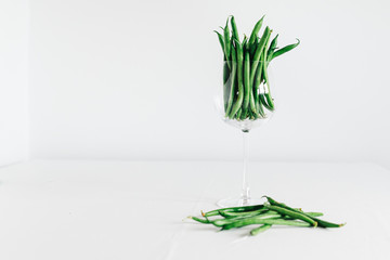 green beans in glass in front of white background