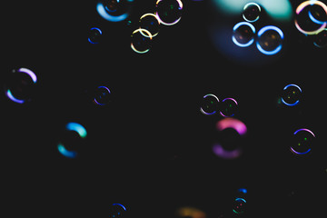 Colorful soap bubbles flying over darck background, shallow depth of field