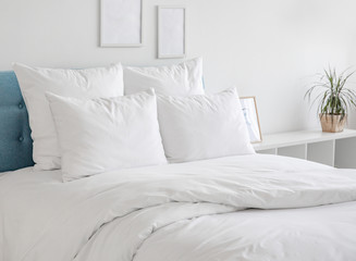 White pillows and duvet on the blue bed. White pillows, duvet and duvet case on a blue bed. White bed linen on a blue sofa. Bedroom with bed and bedding and poster frame mock up on the wall.Front view - obrazy, fototapety, plakaty