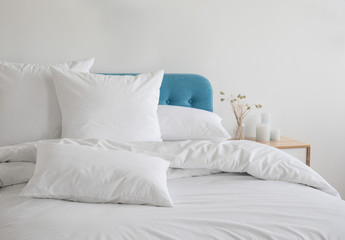 Fototapeta na wymiar White pillows and duvet on the blue bed. White pillows, duvet and duvet case on a blue bed. White bed linen on a blue sofa. Bedroom with bed and beddin.Front view