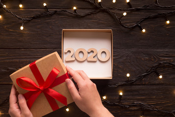 Woman find new 2020 year pesent among garlands on wood