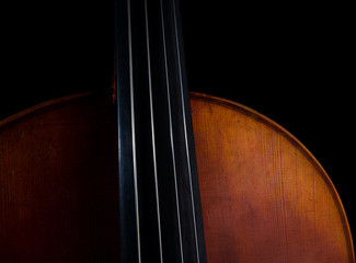 Close up high resolution photo of a cello, showing strings, body, and upper bout isolated against a black background