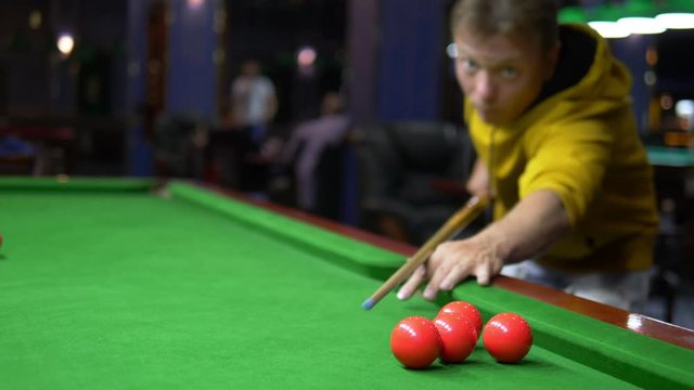 young male professional pool player playing snooker.