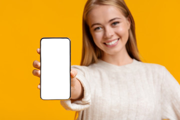 Cute teen girl demonstrating smartphone with blank screen
