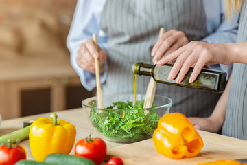Woman adding olive oil to healthy veggies salad