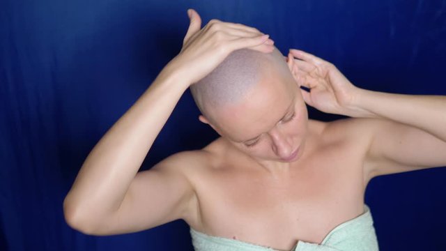 Puzzled bald woman rubs hair growth agent in her head. strange people adventure concept